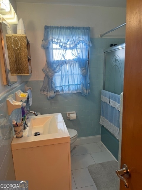 full bathroom with vanity, toilet, tile patterned flooring, tile walls, and combined bath / shower with glass door