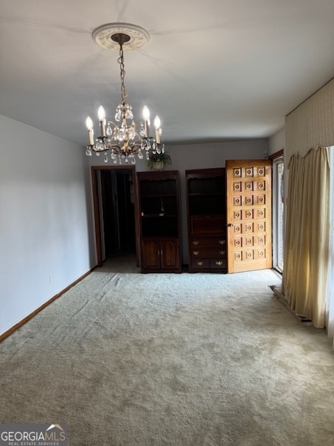 spare room featuring a notable chandelier and carpet flooring