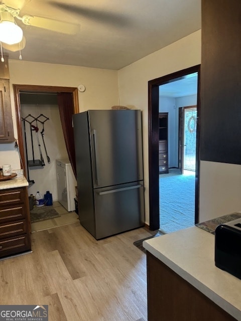 kitchen with stainless steel refrigerator, light hardwood / wood-style floors, and dark brown cabinets