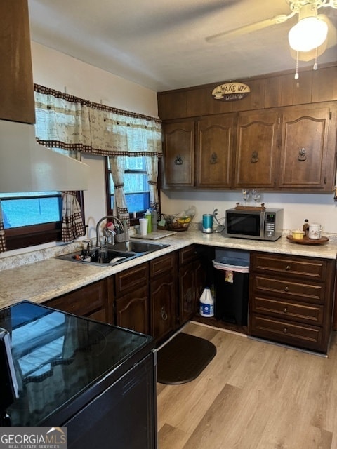 kitchen with dark brown cabinets, electric range, sink, light hardwood / wood-style flooring, and ceiling fan