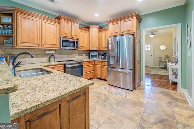 kitchen featuring light stone counters, sink, appliances with stainless steel finishes, crown molding, and decorative backsplash