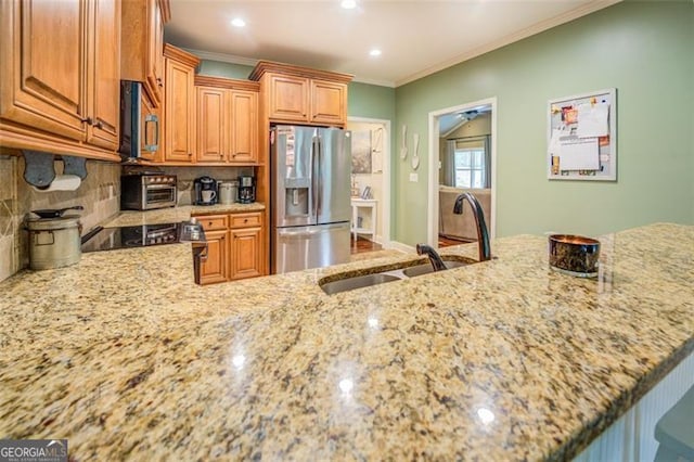 kitchen featuring light stone counters, sink, stainless steel appliances, backsplash, and ornamental molding