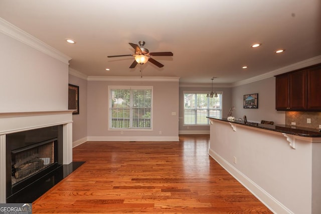 kitchen with ornamental molding, a breakfast bar, light wood-style flooring, and a peninsula