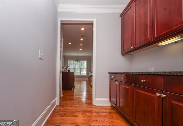 corridor featuring light wood-style floors, baseboards, ornamental molding, and recessed lighting