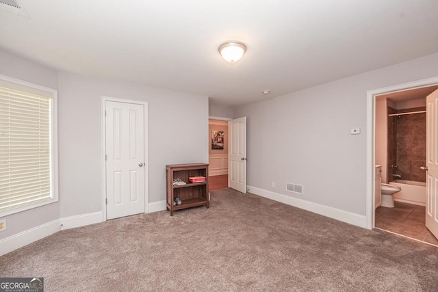 unfurnished bedroom featuring baseboards, visible vents, carpet flooring, and ensuite bathroom