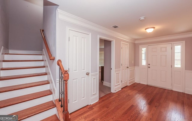 entryway featuring visible vents, crown molding, stairway, and wood finished floors