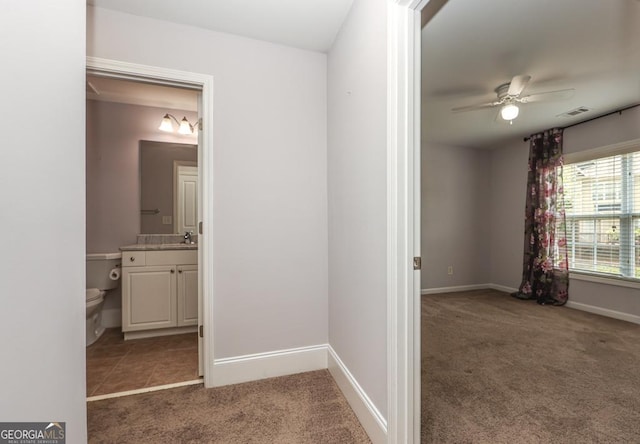 hallway featuring carpet floors, baseboards, visible vents, and a sink