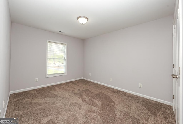 spare room with carpet floors, baseboards, and visible vents