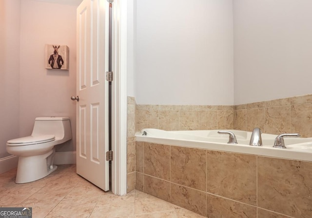 bathroom with tile patterned flooring, a garden tub, and toilet