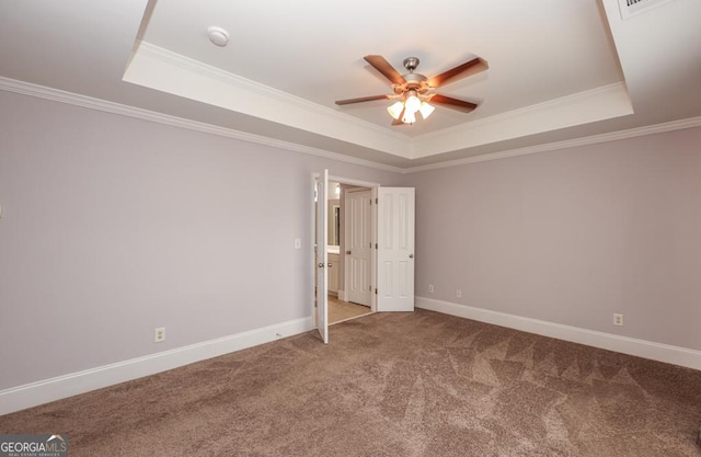 carpeted spare room featuring baseboards, a tray ceiling, and crown molding