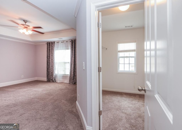 interior space featuring visible vents, baseboards, ornamental molding, a tray ceiling, and carpet floors