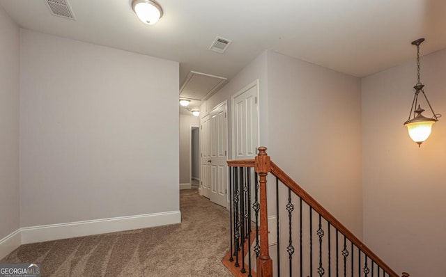 corridor with attic access, visible vents, baseboards, an upstairs landing, and carpet floors