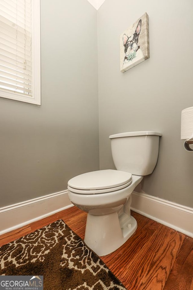 bathroom featuring toilet, baseboards, and wood finished floors