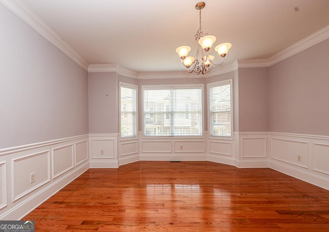 unfurnished dining area featuring a chandelier, wood finished floors, and ornamental molding