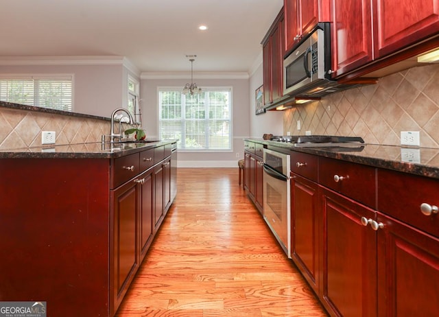 kitchen with reddish brown cabinets, appliances with stainless steel finishes, a sink, and ornamental molding