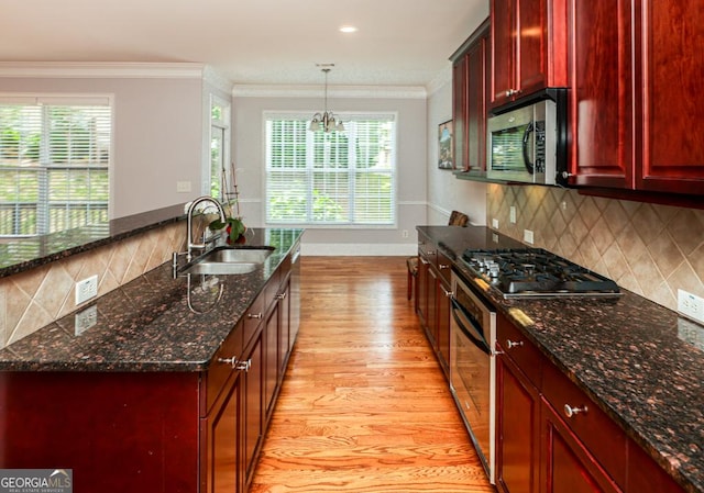 kitchen featuring stainless steel appliances, a sink, light wood-style floors, reddish brown cabinets, and crown molding