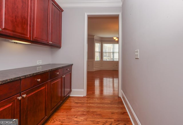 hallway featuring light wood-type flooring, baseboards, and crown molding