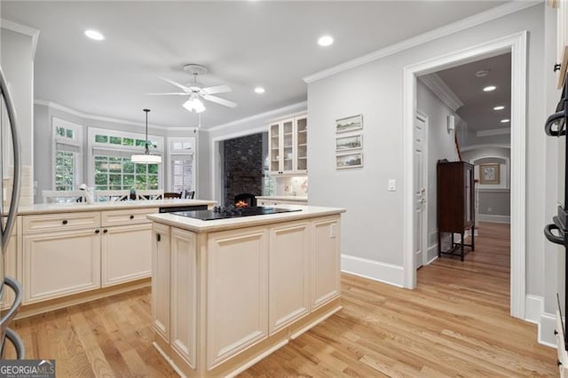 kitchen featuring ceiling fan, light hardwood / wood-style flooring, a center island, black electric stovetop, and a fireplace