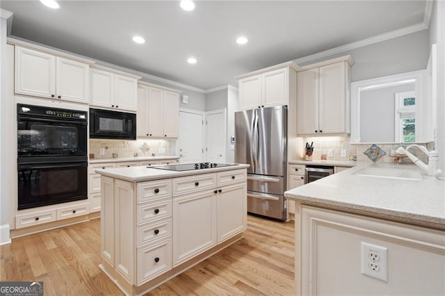 kitchen with light hardwood / wood-style flooring, black appliances, ornamental molding, and sink