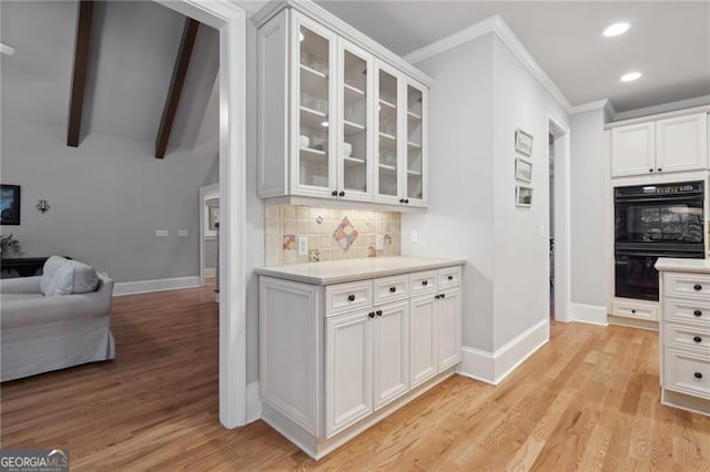 kitchen featuring white cabinets, double oven, and light hardwood / wood-style flooring