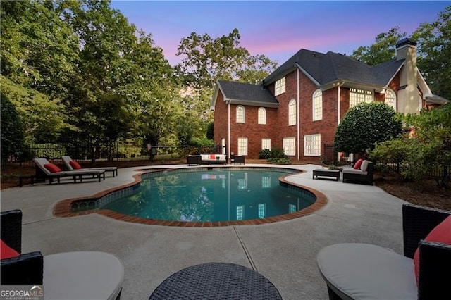 pool at dusk featuring a patio area