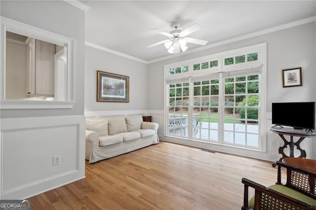 living room with ornamental molding, light wood-type flooring, and ceiling fan