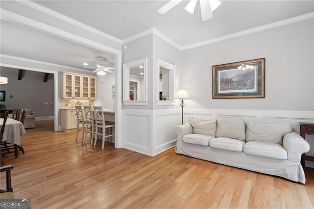 living room featuring ceiling fan, light wood-type flooring, and crown molding