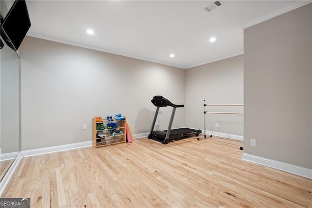 exercise area featuring light hardwood / wood-style flooring and ornamental molding