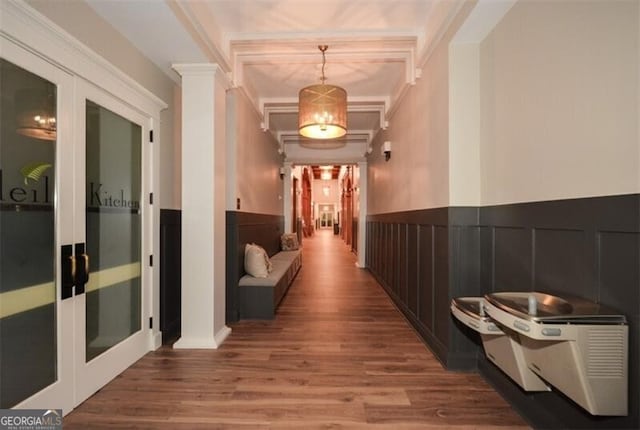 hallway with hardwood / wood-style floors, ornamental molding, and a chandelier