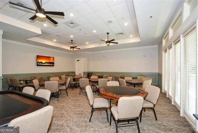 dining space featuring a raised ceiling, ceiling fan, light carpet, and ornamental molding