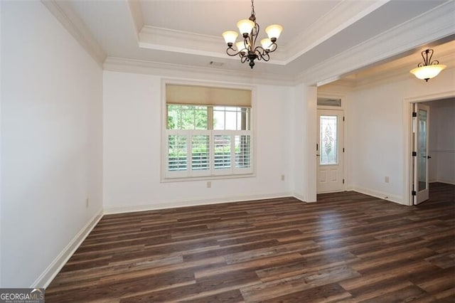 spare room featuring a raised ceiling, dark hardwood / wood-style flooring, crown molding, and an inviting chandelier