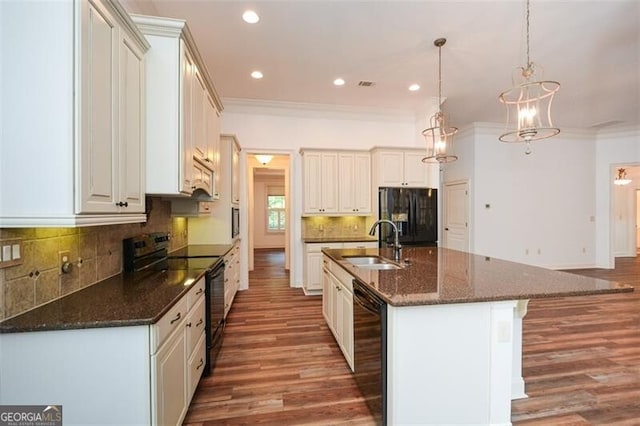 kitchen with hanging light fixtures, dark wood-type flooring, an island with sink, and black appliances