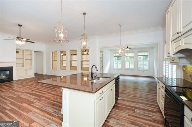 kitchen featuring a center island with sink, dark hardwood / wood-style floors, dark stone counters, and sink