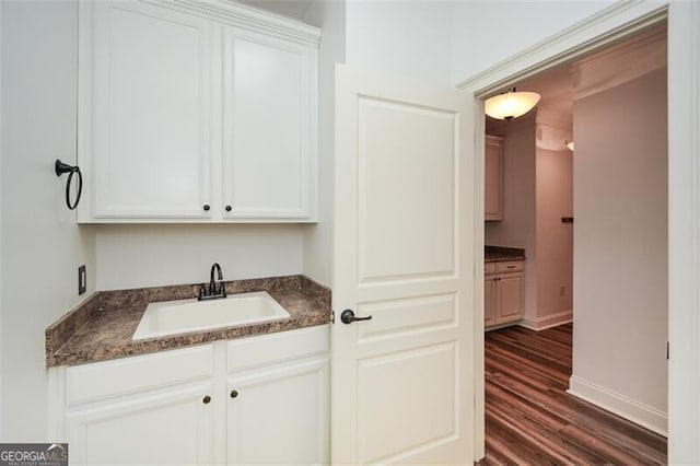 bar featuring white cabinetry, dark wood-type flooring, and sink