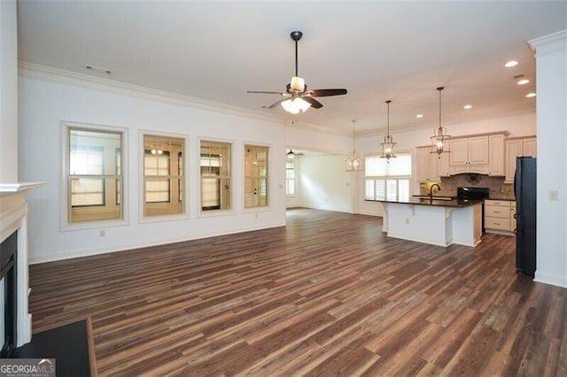 unfurnished living room featuring ceiling fan, sink, dark hardwood / wood-style floors, and ornamental molding