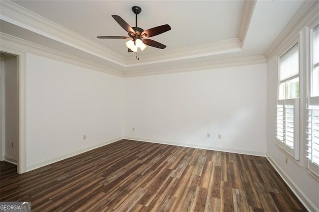 unfurnished room with ceiling fan, a raised ceiling, ornamental molding, and dark wood-type flooring