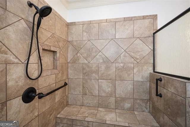 bathroom featuring tiled shower and crown molding