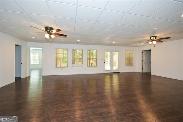 unfurnished living room with dark hardwood / wood-style flooring, a drop ceiling, and ceiling fan