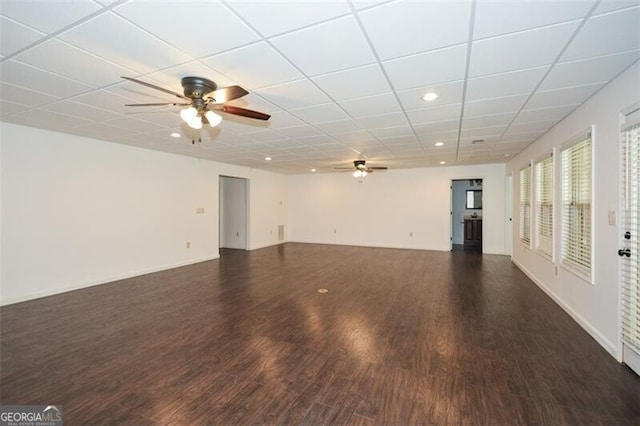 empty room with ceiling fan, a drop ceiling, and dark wood-type flooring