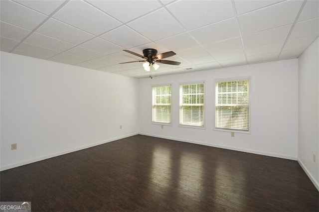 empty room with dark hardwood / wood-style floors, ceiling fan, and a drop ceiling