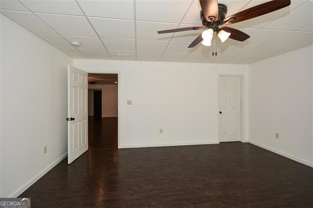 spare room featuring ceiling fan, dark hardwood / wood-style flooring, and a drop ceiling