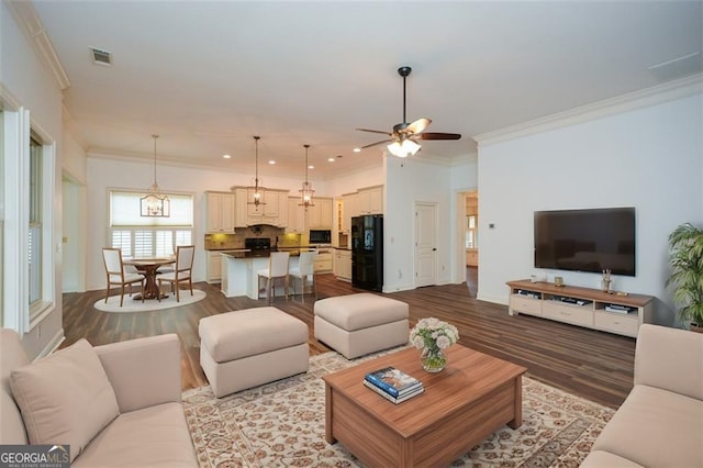 living room with wood-type flooring, ceiling fan with notable chandelier, and crown molding