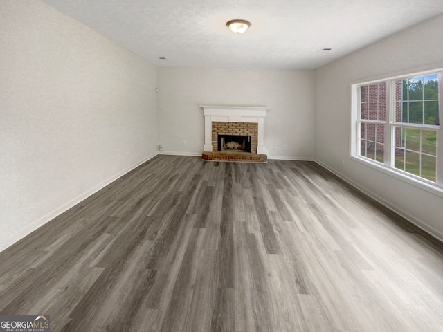 unfurnished living room with a brick fireplace, wood-type flooring, and a textured ceiling