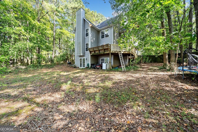 back of house with a wooden deck and a trampoline