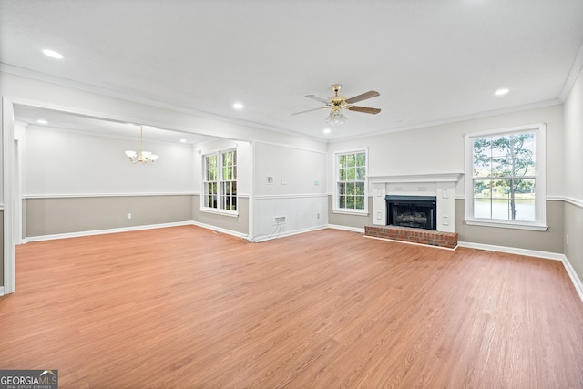 unfurnished living room with crown molding, ceiling fan with notable chandelier, a fireplace, and light wood-type flooring