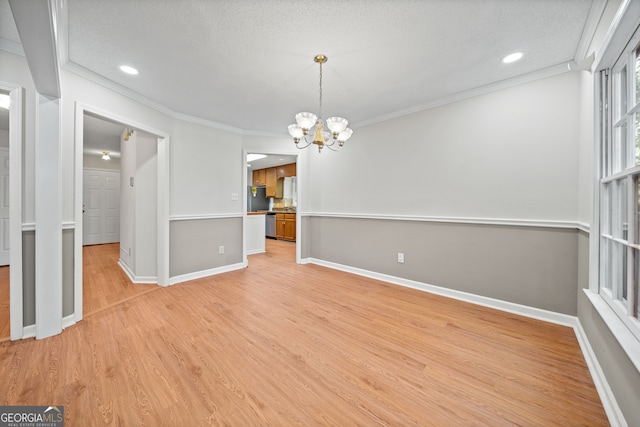 interior space with crown molding, light hardwood / wood-style flooring, a textured ceiling, and an inviting chandelier