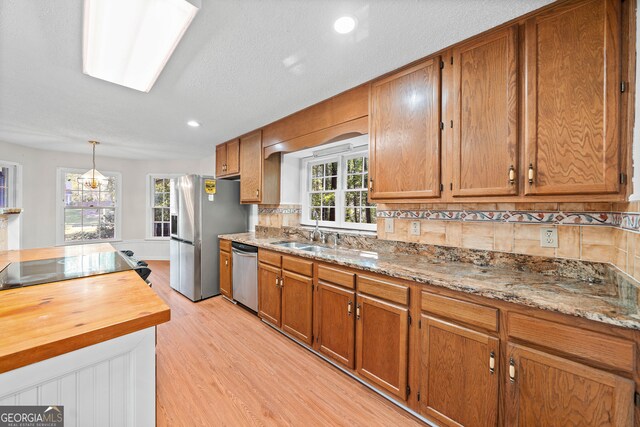 kitchen with decorative backsplash, stainless steel appliances, light wood-type flooring, and a wealth of natural light