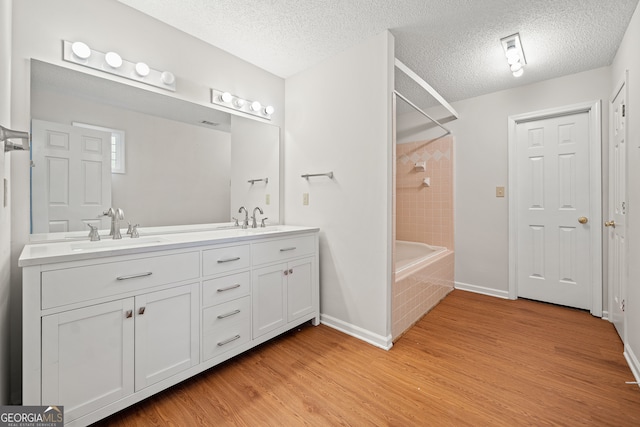 bathroom featuring vanity, hardwood / wood-style flooring, a textured ceiling, and tiled shower / bath