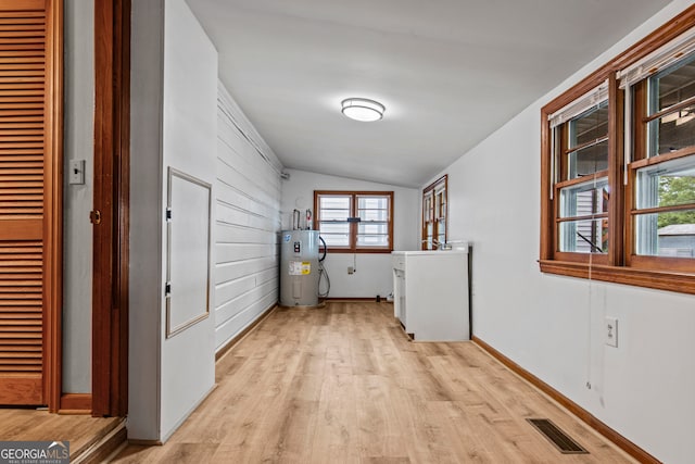 laundry room featuring electric water heater and light wood-type flooring