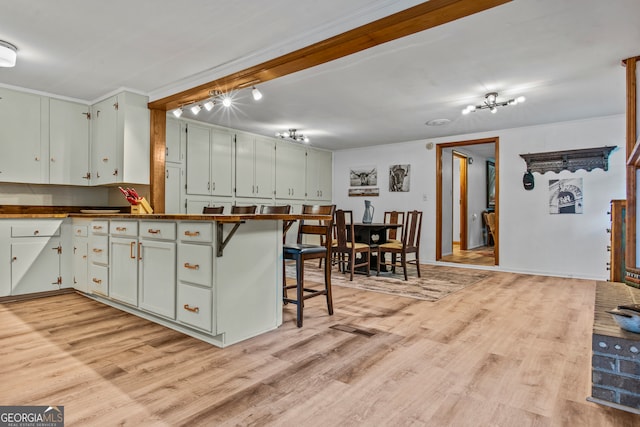 kitchen with kitchen peninsula, white cabinetry, a breakfast bar, and light hardwood / wood-style flooring